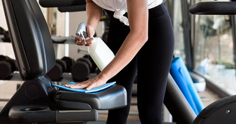 A person cleaning a gym machine A person cleaning a gym machine