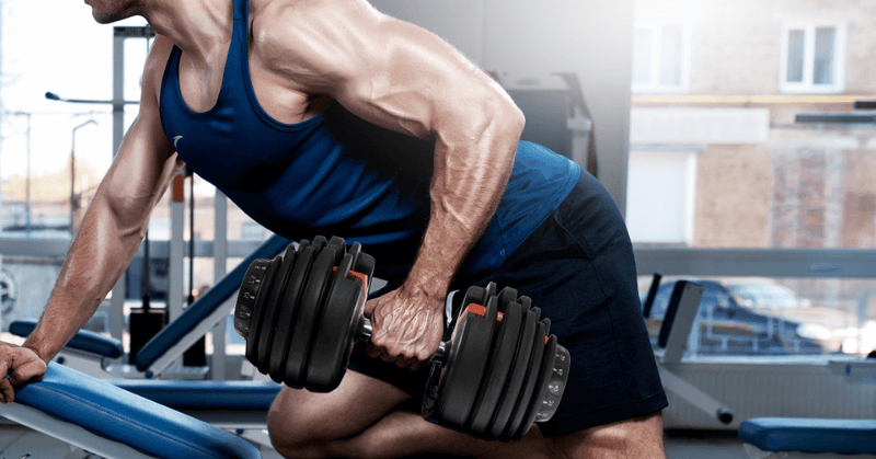 Man in gym doing adjustable dumbbell rows