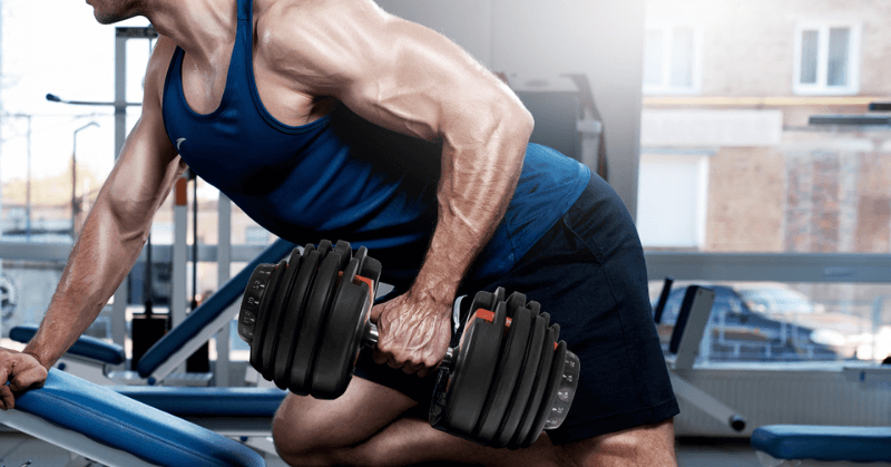 Man in gym doing adjustable dumbbell rows Man in gym doing adjustable dumbbell rows