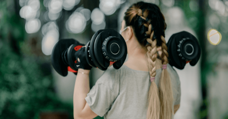 Woman doing shoulder presses with adjustable dumbbells