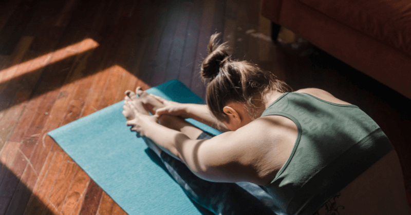 Woman stretching forwards on a yoga mat