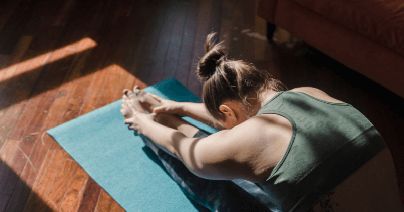 Woman stretching forwards on a yoga mat Woman stretching forwards on a yoga mat